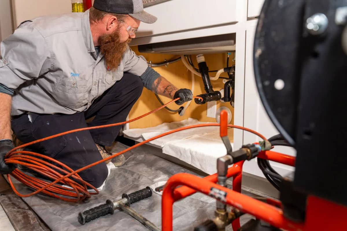 Done Rite Services expert plumber works diligently beneath a kitchen sink in Tucson, clearing a stubborn blockage with specialized tools. This essential service ensures smooth water flow and prevents potential plumbing issues, showcasing the company's commitment to quality and efficiency