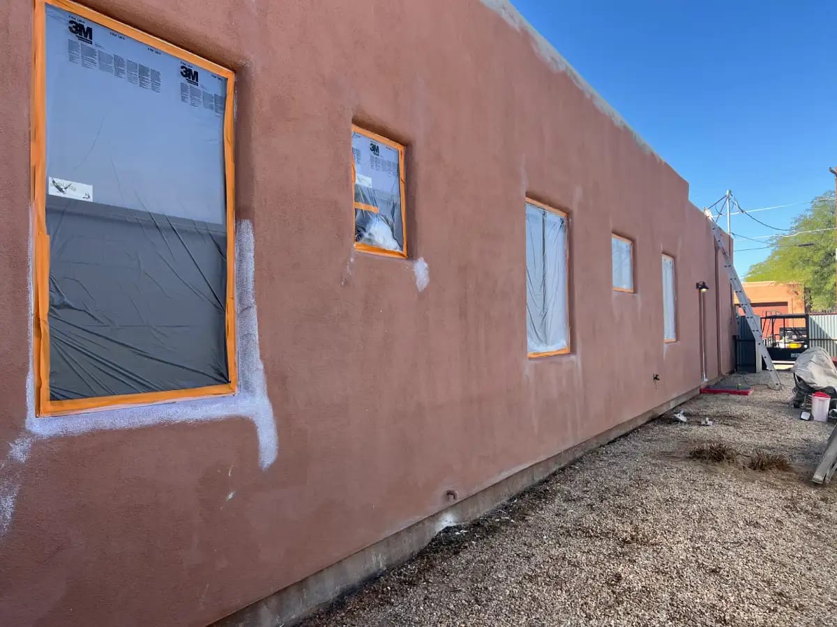 Preparation of a residential stucco wall, with plastic sheeting on the window for the stucco repair process